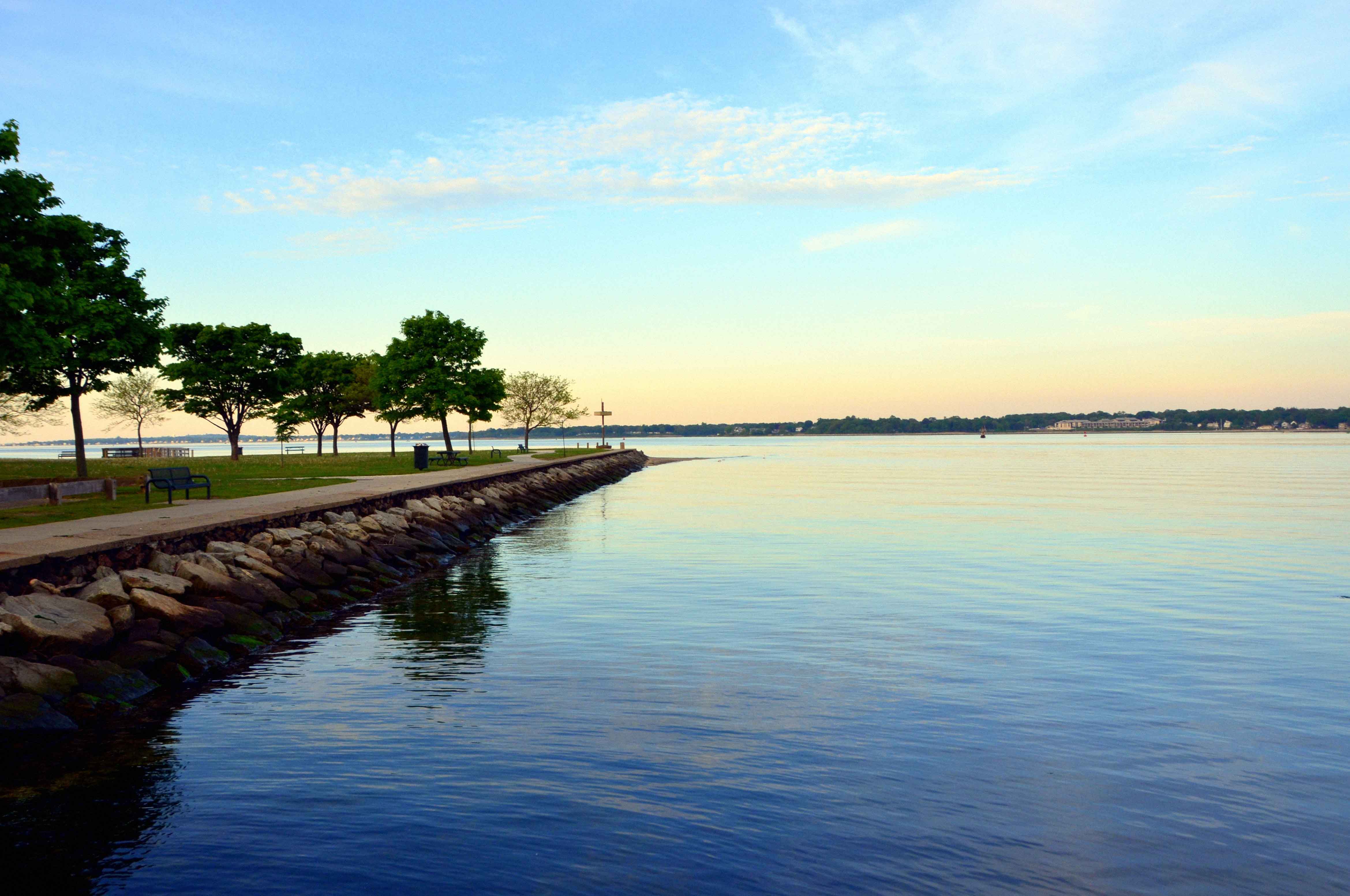 Sunset over the water at Sabin Point, Riverside, Rhode Island, with a tree-lined shoreline path